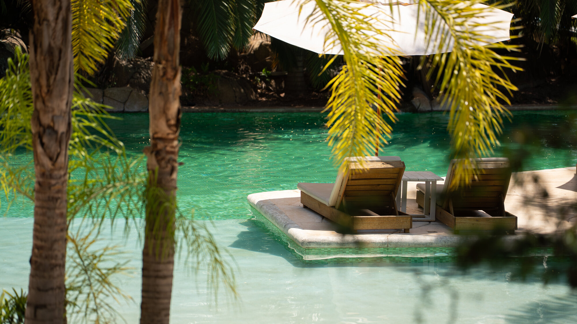 Piscina da Baguá Bangalôs com espreguiçadeiras e palmeiras